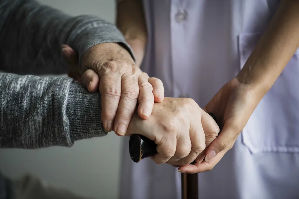 Nurse holding hands with a senior in a living room